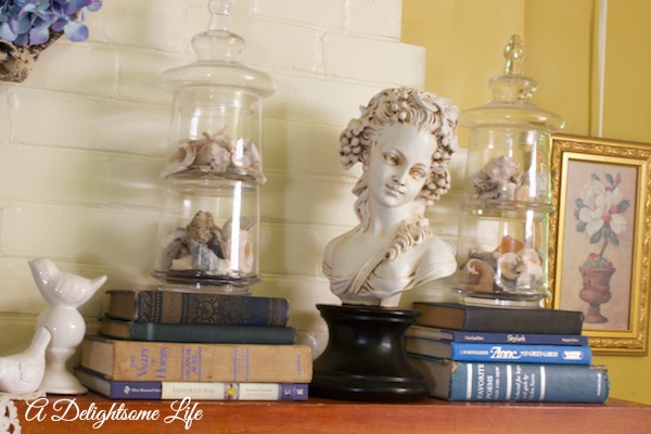 A DELIGHTSOME LIFE SUMMER MANTEL LADY BUST WHITE BIRDS GLASS CANNISTERS SEA SHELLS BOOKS
