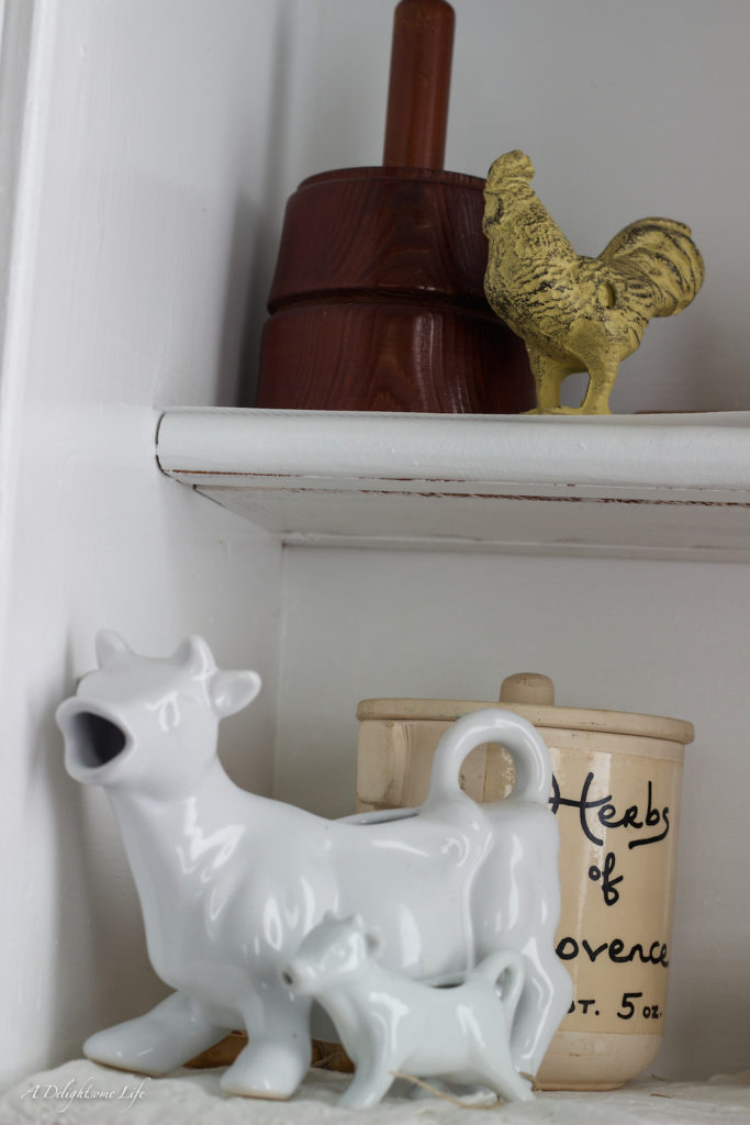 French Farmhouse decor details include these sweet cow pitchers, wrought iron rooster and butter mold