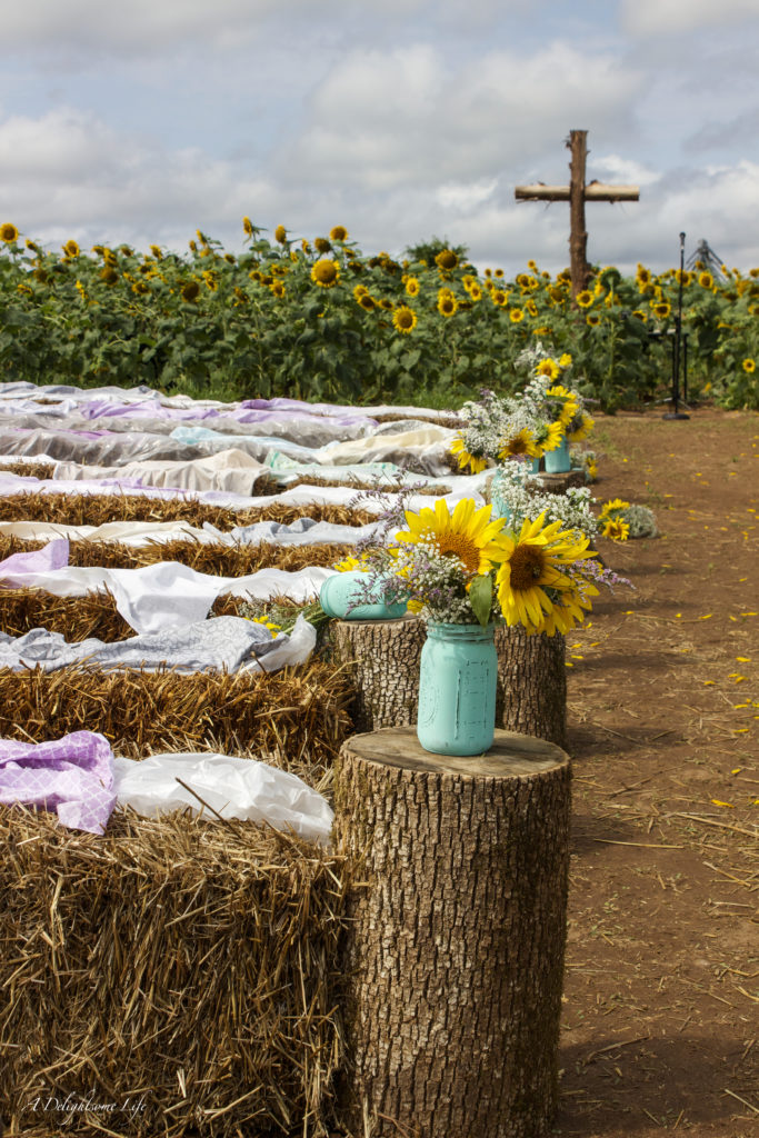 hay bales, painted mason jars and a rugged cross were some of the DIY decor elements my daughter envisioned for her wedding in a sunflower field
