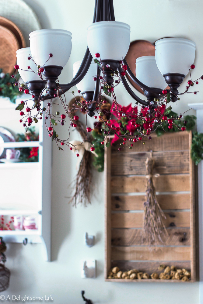 simple berry garland strung along the kitchen chandelier lights add Christmas charm on A Delightsome Life